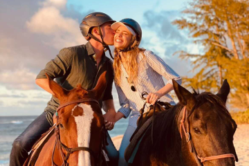 Couple riding horses on the beach