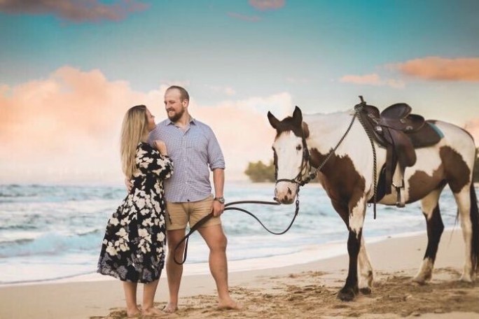 a man and a woman photoshoot with horse on a beach